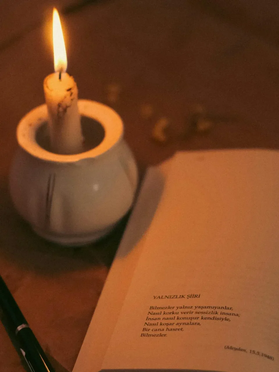 An open book illuminated by candlelight, creating a warm and serene ambiance.